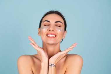 Mükemmel ciltli, doğal makyajlı, gözlerinin altında parlak lekeler olan üstsüz bir kadının güzel portresi cildinizi nemlendirir ve yüzünüzün şişkinliğini giderir.