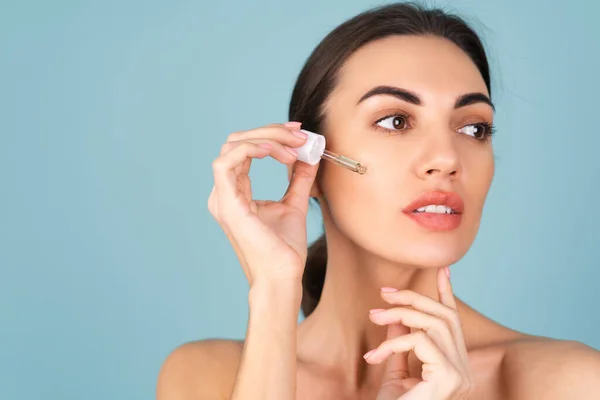 Mükemmel ciltli ve doğal makyajlı üstsüz kadının yakın güzellik portresi, gençlik ve cilt suyu için serum, kozmetik yağlı damlatıcı.