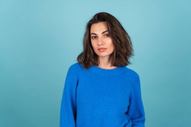 Woman in a blue knitted sweater and natural makeup, curly short hair, look to camera with confident smile clipart