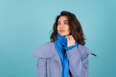 İlkbahar portresi mavi örgü süveter, atkı ve gri ceketli bir kadın, neşeyle poz veriyor, gülümsüyor, bahar beklentisiyle