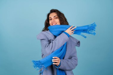 İlkbahar portresi mavi örgü süveter, atkı ve gri ceketli bir kadın, neşeyle poz veriyor, gülümsüyor, bahar beklentisiyle