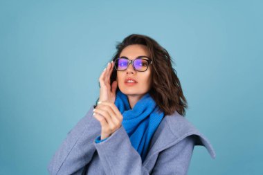 İlkbahar portresi, mavi örgü süveter, atkı ve gri ceketli bir kadın, bahar beklentisiyle şık poz veriyor.