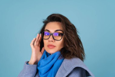 İlkbahar portresi, mavi örgü süveter, atkı ve gri ceketli bir kadın, bahar beklentisiyle şık poz veriyor.