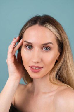 Mükemmel ciltli ve doğal makyajlı üstsüz bir kadının yakın plan güzel portresi. Gözlerinin altındaki deriyi nemlendirmek ve sertleştirmek için anti-yaşlandırıcı krem noktaları var.