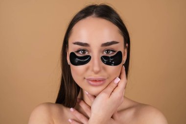 Mükemmel ciltli, doğal makyajlı, gözlerinin altında siyah lekeler olan üstsüz bir kadının güzel portresi cildinizi nemlendirir ve yüzünüzün şişkinliğini giderir.