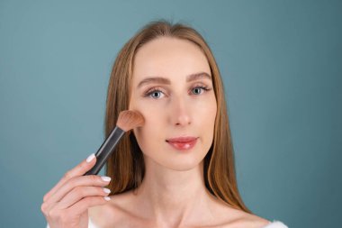 Mükemmel ciltli, doğal makyajlı, tamamen çıplak dudaklı, kırmızı bir fırça tutan üstsüz bir kadının yakın plan güzel portresi.