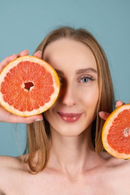 Mükemmel ciltli, doğal makyajlı, çıplak dudaklı, taze narenciye vitamini ve greyfurt içeren üstsüz kadın portresi.