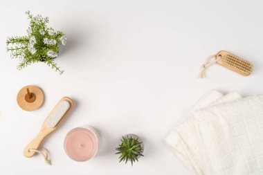 Düz yatak, modern banyo dekorasyonu. Havlular, ahşap çevre dostu fırçalar ve beyaz arka planda cam kavanozda bir mum..