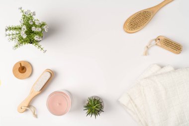 Düz yatak, modern banyo dekorasyonu. Havlular, ahşap çevre dostu fırçalar ve beyaz arka planda cam kavanozda bir mum..