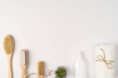Flatlay, modern banyo dekoru. Havlular, ahşap çevre dostu fırçalar ve beyaz arka planda şampuan..
