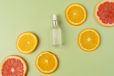 Doğal C vitamini serumu, cilt bakımı, gerekli yağlar. Kozmetik cam şişesi, damlatıcı, sulu portakal ve greyfurt dilimleri..