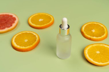 Doğal C vitamini serumu, cilt bakımı, gerekli yağlar. Kozmetik cam şişesi, damlatıcı, sulu portakal ve greyfurt dilimleri..