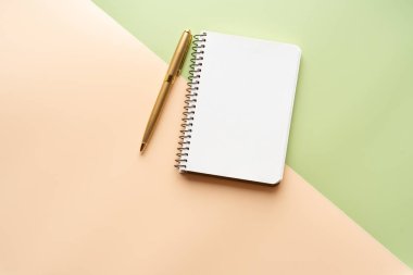 İki rengin arka planı, açık yeşil ve şeftali rengi. Üst manzara, duvar kağıdı. Not defteri ve altın kalem..