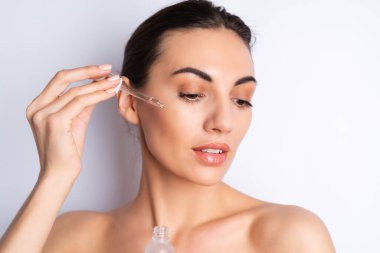 Mükemmel ciltli ve doğal makyajlı üstsüz kadının yakın güzellik portresi, gençlik ve cilt suyu için serum, kozmetik yağlı damlatıcı.