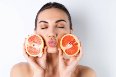 Mükemmel ciltli, doğal makyajlı, çıplak dudaklı, taze narenciye vitamini ve greyfurt içeren üstsüz kadın portresi.