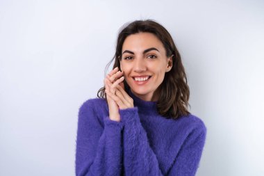 Mor yumuşak süveter giyen genç bir kadın tatlı bir gülümseme, neşeli, kendine güvenen bir gülümseme