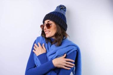 Young woman in a blue golf turtleneck, hat and scarf, sunglasses, on a white background, cheerful in a good mood clipart