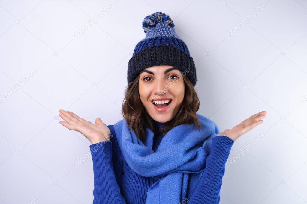 Young woman in a blue golf turtleneck, hat and scarf, on a white background, cheery in a good mood
