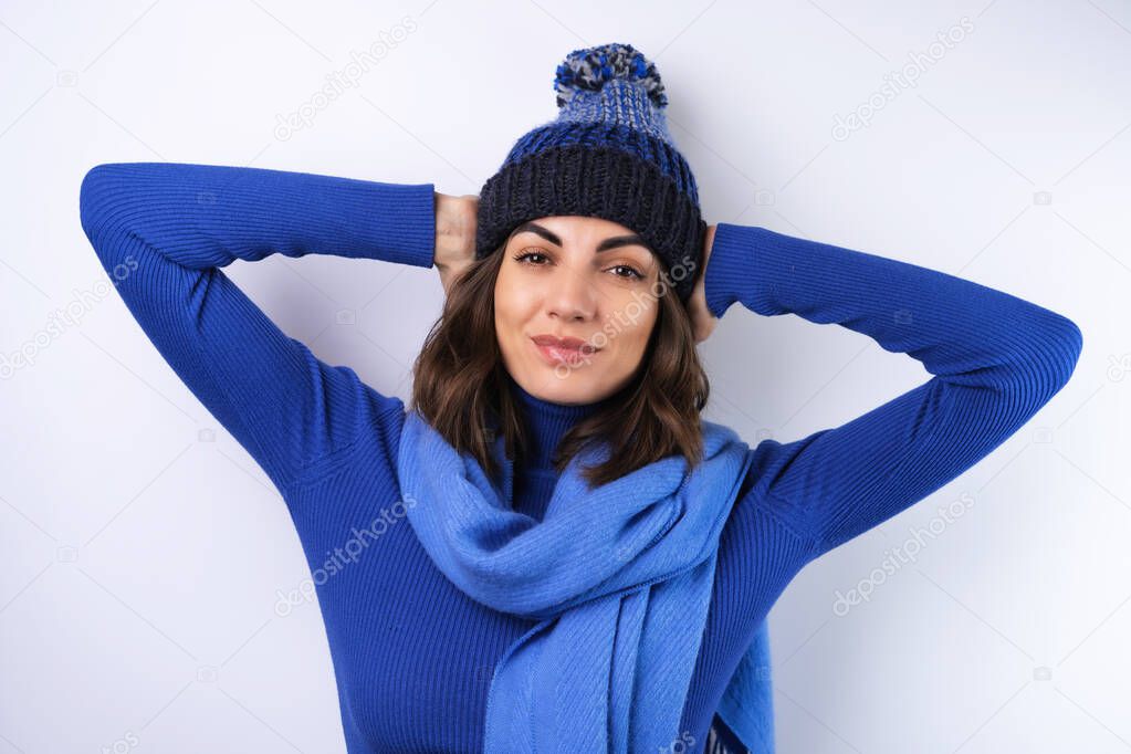 Young woman in a blue golf turtleneck, hat and scarf, on a white background, cheery in a good mood