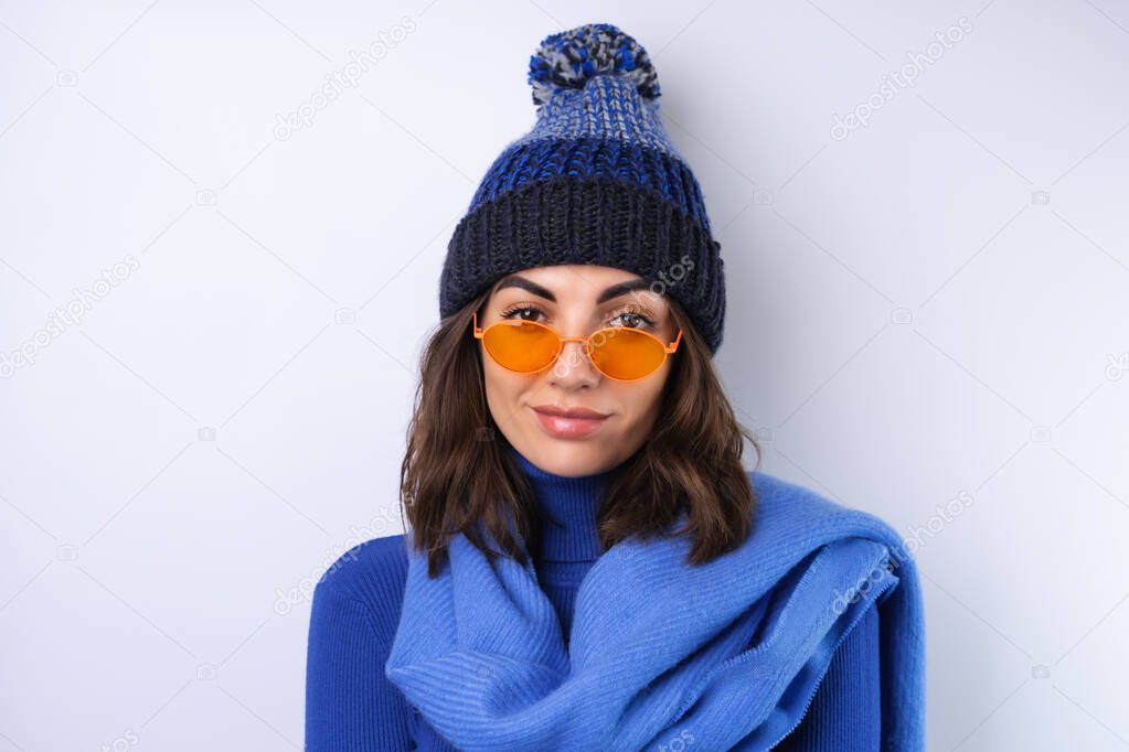 Young woman in a blue golf turtleneck, hat and scarf, sunglasses, on a white background