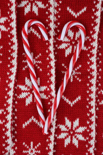 赤と白のニットウールの背景にキャンディ杖の装飾で作られたハート型 クリスマスのお祝いの背景 — ストック写真