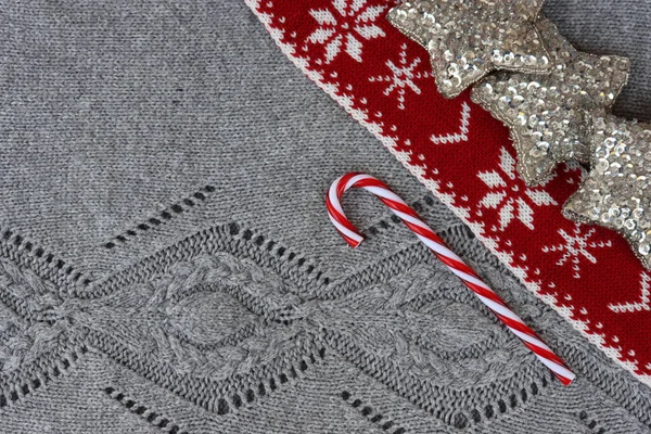 グレーは 赤と白のクリスマスウールのスカーフとキャンディーの杖でニットウールの背景を飾りました クリスマスのお祝いの背景 — ストック写真