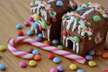 Şeker kaplı küçük zencefilli evler ve ahşap masa üzerine şekerleme süslemeleri. Noel arkaplanı