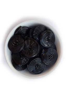 Beyaz arka planda izole edilmiş beyaz bir kasede siyah meyan kökü tekerlekleri.