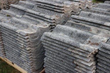  Eski gri beton çatı kiremitleri yığılmış.