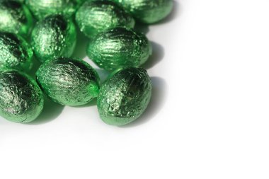 Beyaz arka planda izole edilmiş yeşil folyoyla çikolatalı paskalya yumurtaları.