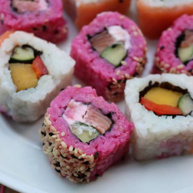 Pancar suyuyla boyanmış Japon somonu. İçi dışa dönük. Tahta masada meyve ve sebze tabağı var.