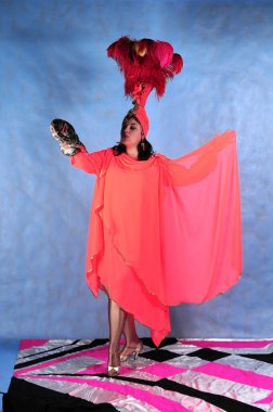 Mavi arka planda tüyleri olan, pembe elbiseli yılan pitonlu animatör kadın.