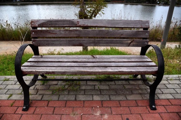 池塘边公园人行道上的长椅 — 图库照片