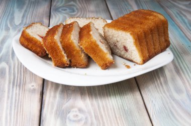 Kek, tahta bir arka planda beyaz bir tabakta taze dilimlenmiş.