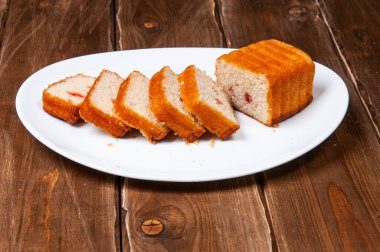 Kek, tahta bir arka planda beyaz bir tabakta taze dilimlenmiş.