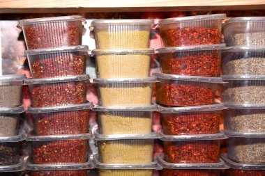 Marketin rafındaki plastik şeffaf kaplarda renkli baharatlar.