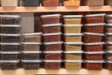 Marketin rafındaki plastik şeffaf kaplarda renkli baharatlar.