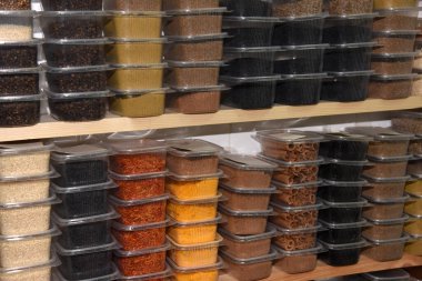 Marketin rafındaki plastik şeffaf kaplarda renkli baharatlar.