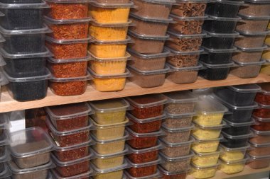 Marketin rafındaki plastik şeffaf kaplarda renkli baharatlar.