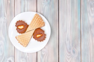 Ağız sulandıran iki kalp şeklinde kek ve ahşap bir arka planda beyaz çay tabağında iki turta.