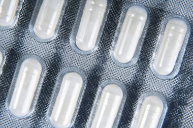 Vücudun tedavisi için beyaz haplarla birlikte plastik ambalajın dokulu yüzeyi