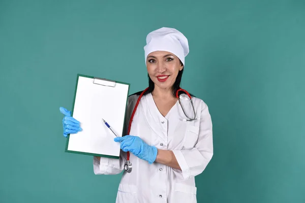 一名身穿白色外套 头戴白色头饰的女医生在平板电脑上放有带绿色背景听诊器的录音 — 图库照片