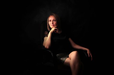 Stüdyo 'nun alacakaranlığında koltuğun siyah arka planında muhteşem bir sarışın.