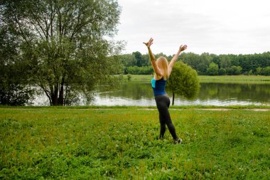 Parktaki sarışın ellerini sallayarak göletteki temiz havayı seviyor.