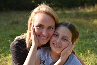 Anne ve kızı yanak yanağa gülümsüyor.