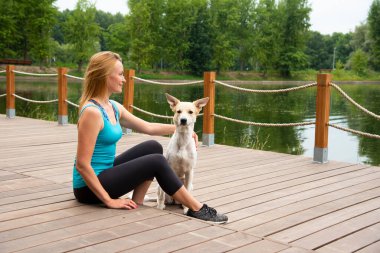 İskelede sarışın, spor elbiseli bir köpekle yaz günü