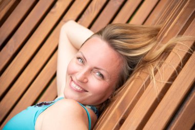 Sarışın, bir yaz günü bankta uzanmış hayatın tadını çıkarıyor.