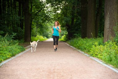 Yazın bir köpekle parkta koşuşturan güzel kız.