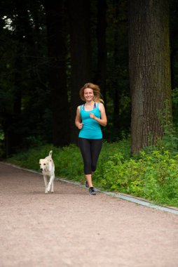 Yazın bir köpekle parkta koşuşturan güzel kız.
