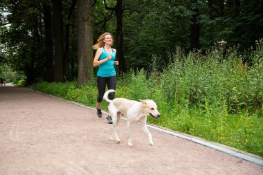 Yazın bir köpekle parkta koşuşturan güzel kız.